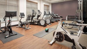 Une salle de sport équipée de tapis de course, de vélos elliptiques et d’un vélo de spinning.
