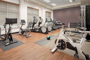 Uma academia com esteiras, elípticos e bicicleta spinning.