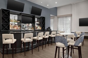 A bar area with a counter, multiple seating options including bar stools and chairs, and a television mounted on the wall. - Two King Room at a  Hotel (Birmingham)
