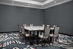 A conference room with a rectangular table surrounded by chairs, a patterned carpet, and a plain wall. - Two King Room at a  Hotel (Birmingham)