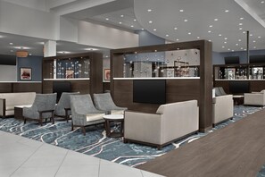 A modern hotel lobby with seating areas, a reception desk, and a decorative wall with hanging mirrors. - Two King Room at a  Hotel (Birmingham)