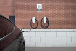 A parking area with a brick wall and two electric vehicle charging stations. - Two King Room at a  Hotel (Birmingham)