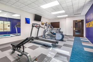 Una palestra con tapis roulant, ellittiche e una panca per pesi.