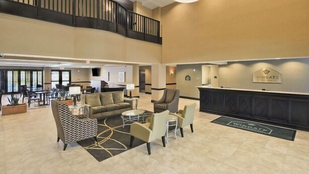 A spacious lobby with a high ceiling, a staircase, and a reception desk.