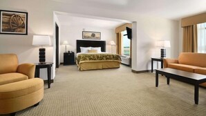 A hotel room with a bed, two armchairs, a coffee table, and a TV.