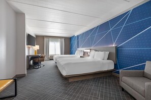 A hotel room with a large bed, a desk with a chair, a TV, and a blue accent wall. - 2 Connecting Suites at a  Hotel (Frisco)
