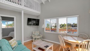 Une chambre avec balcon, un téléviseur fixé au mur, une table à manger avec des chaises et une vue sur un port de plaisance.