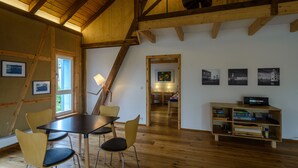 Ein Essbereich mit einem Holztisch und Stühlen, einem Bücherregal und gerahmten Bildern an den Wänden.
