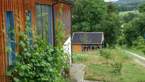 Ein rustikales Holzgebäude mit großen Fenstern und einem Garten mit einem Weg zu einer kleineren Struktur.