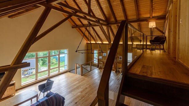 Ein geräumiges Schlafzimmer im Loft-Stil mit hohen Decken, großen Fenstern und Holzboden.