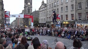 A street performance with a crowd gathered around a performer on a unicycle. - Morrison Central ApartHotel Edinburgh (Edinburgh)