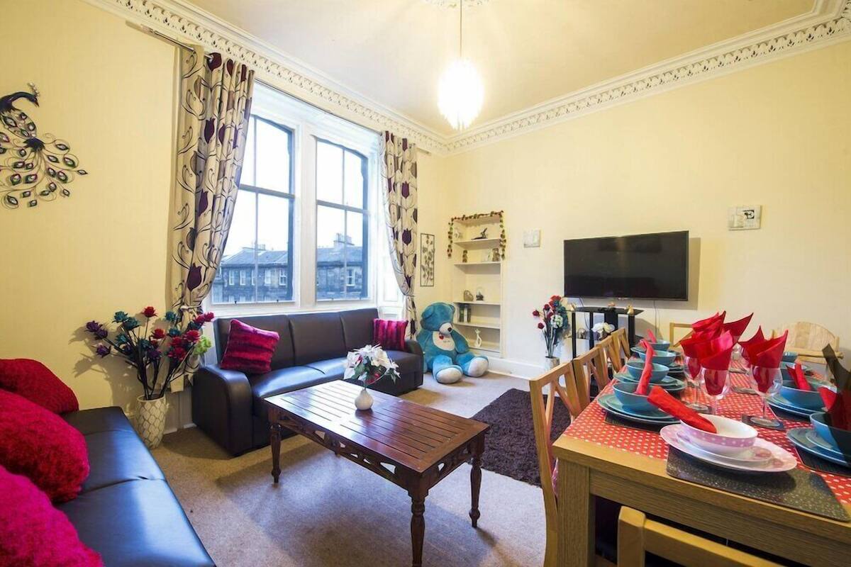 A living room with a sofa, coffee table, and dining table set for a meal.