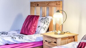 A neatly made bed with a floral-patterned duvet, a wooden headboard, and a bedside lamp. - Morrison Central ApartHotel Edinburgh (Edinburgh)