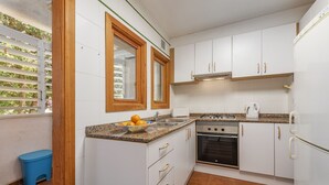 Eine kleine Küche mit weißen Schränken, einem Gasherd und einem eingebauten Backofen.
