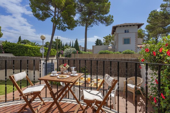 An outdoor dining area with a table set for two, surrounded by wicker chairs. - Apartment Bugambilia meters from the beach private garden (Puerto Pollensa)