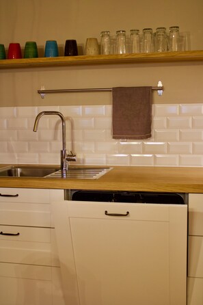 Enjoy cooking in this well-equipped kitchen with a stainless steel sink, wooden countertop, and ample cabinetry.