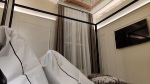 A room with a white sofa, a large window with sheer curtains, a flat-screen TV mounted on the wall, and a decorative ceiling. - La Bella Modena Centro (Modena)
