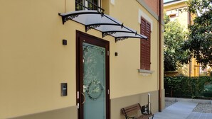 A yellow building with a glass door, a bench, and a metal umbrella. - La Bella Modena Centro (Modena)