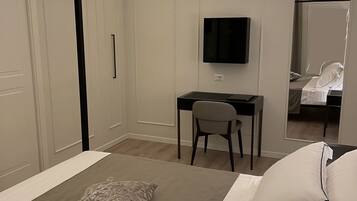 Un dormitorio con cama, escritorio, silla, televisor y armario.