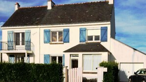 A two-story house with a balcony, a garage, and a car parked in front. - Maison 6 Chambres Carnac Proche Plage - 9 Couchages (Carnac)
