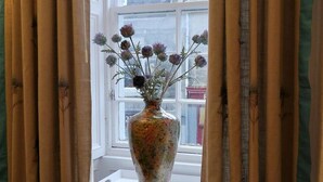 Ein Fenster mit einer Blumenvase auf einem weißen Tisch.