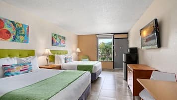 A hotel room with two beds, a desk, a TV, and artwork on the walls.