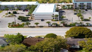 A multi-story hotel with a flat roof, parking lot, and surrounding greenery.