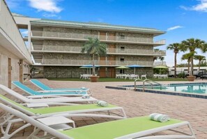 A hotel with a pool area, lounge chairs, and a multi-story building with balconies. - Stylish Room with 2 DBL Beds, Pool & Fitness Center (Kissimmee)