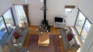 A spacious living room with a fireplace, two sofas, a coffee table, and a TV on a white stand. - Laundry Cottage -  a house that sleeps 8 guests  in 4 bedrooms (Aberlour)