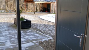 A modern building with a large sliding glass door leading to a covered outdoor area with a wooden structure. - Laundry Cottage -  a house that sleeps 8 guests  in 4 bedrooms (Aberlour)