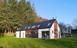 A modern house with a sloped roof, large windows, and a wooden facade.