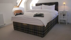 A bedroom with a bed, a nightstand, a lamp, a radiator, and a window. - Laundry Cottage -  a house that sleeps 8 guests  in 4 bedrooms (Aberlour)