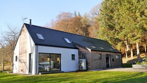 Une maison moderne avec un toit en pente, de grandes fenêtres et une pelouse bien entretenue.