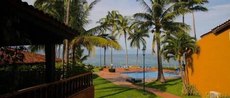 Zona de piscina con palmeras y vista al océano.