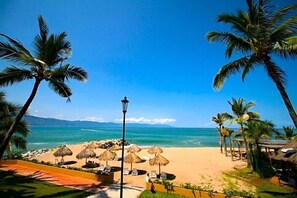 A beach with palm trees, a clear blue sky, and a view of the ocean. - Stylish 1BR Condo with Pool in Park Royal Los Tules (Puerto Vallarta)