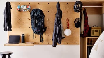 Een kamer met een houten prikbordwand waarop verschillende spullen liggen, zoals een laptop, een rugzak en een helm.