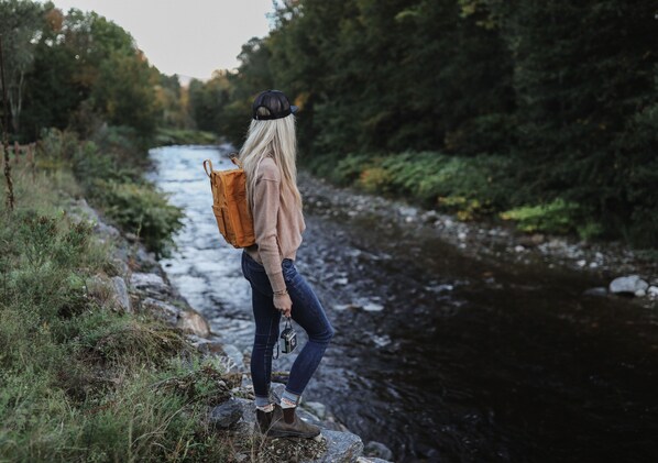 Una persona de pie sobre una roca junto a un río, cargando una mochila.