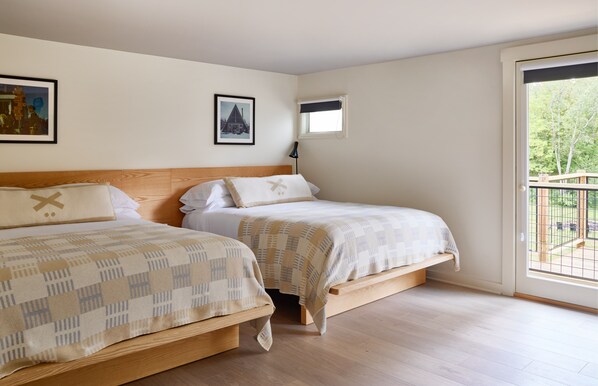 Un dormitorio con dos camas, una ventana que ofrece vistas al exterior y una lámpara de mesa pequeña.
