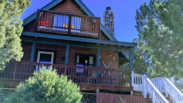 A two-story log cabin with a stone chimney, wooden balconies, and a wooden staircase leading to the entrance. - Pet-Friendly [no fee!] A-Frame Cabin w/ Double-decker Mountain View & Hot Tub (Alto)