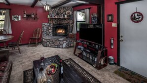 A cozy living room with a stone fireplace, a television, and a bookshelf. - Pet-Friendly [no fee!] A-Frame Cabin w/ Double-decker Mountain View & Hot Tub (Alto)