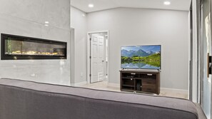 A modern living room with a fireplace, a flat-screen TV, and a door.