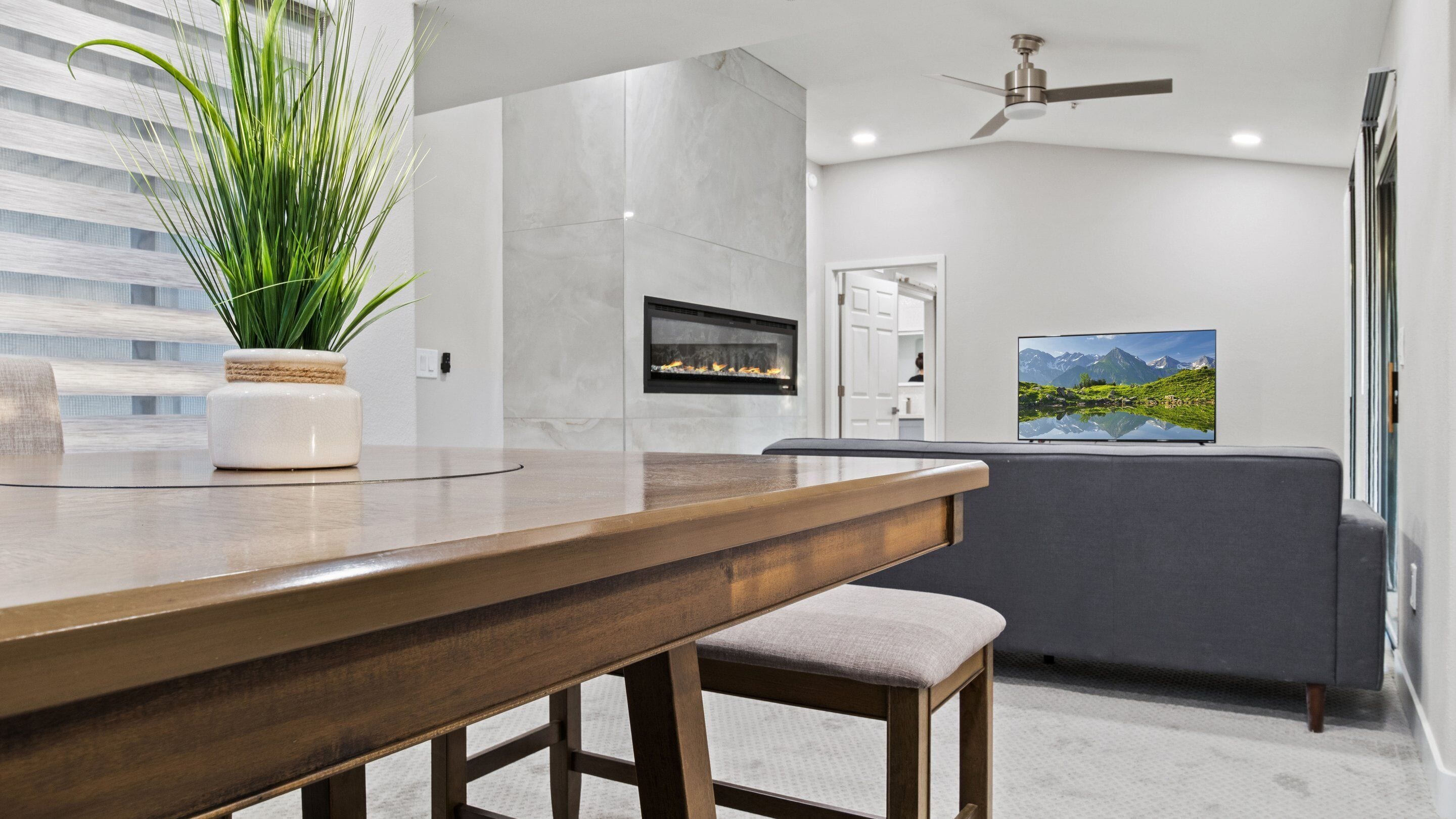 A modern kitchen with a wooden countertop, a built-in stove, and a large window with blinds.