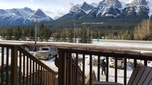 A view from a balcony overlooking snow-covered mountains and a road with vehicles.