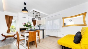 Un espace de vie moderne comprenant un coin repas, une cuisine et un canapé jaune.