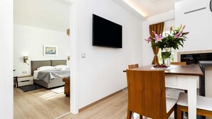 Une chambre d’hôtel moderne équipée d’un lit, d’une table de chevet et d’un téléviseur à écran plat fixé au mur.