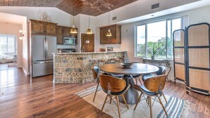 A spacious kitchen with a stone island, wooden cabinets, and a large window offering a view. - Getaway Ranch - Views for Days +  Pool + Game Room (Spicewood)