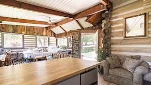 A log cabin interior with a wooden dining table, a sofa, and a stone fireplace. - Meadowlands Cottage, Horse Ranch with Wood Burning Stove and a River, Hot Tub (kernville)