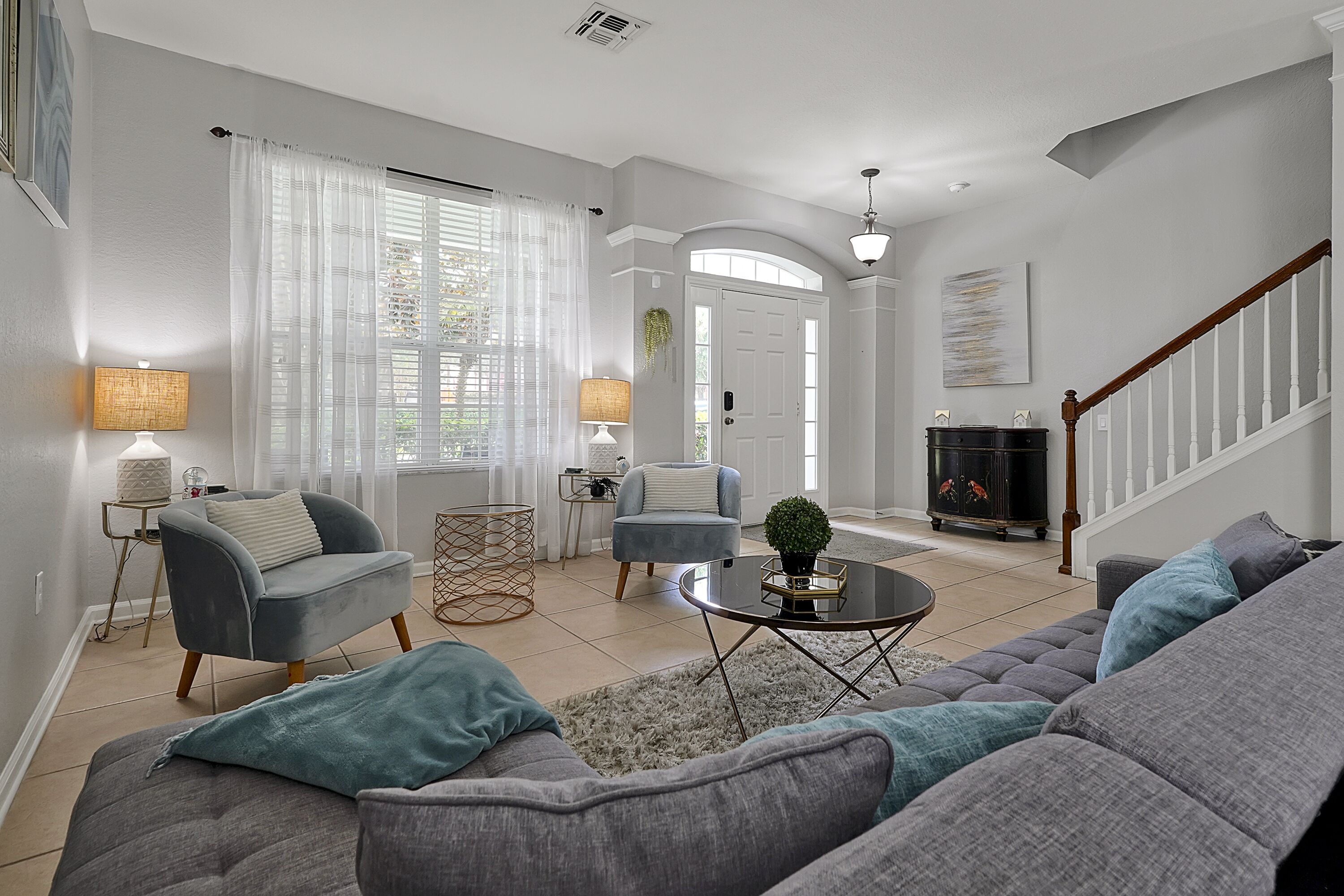 Una sala de estar con un sofá gris, sillones, una mesa de centro y una chimenea.