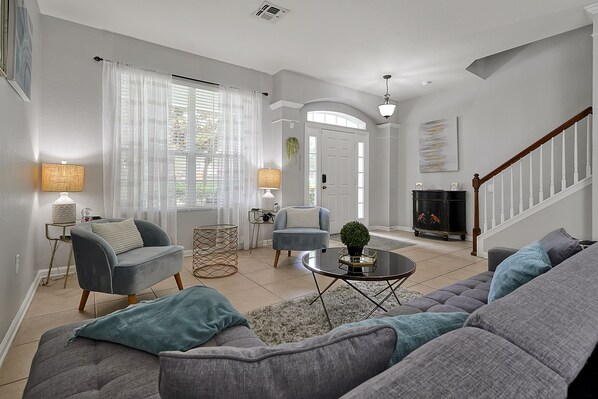 A living room with a grey sofa, armchairs, a coffee table, and a fireplace.