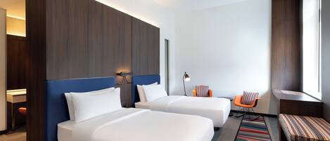 Une chambre d’hôtel avec deux lits, un bureau, une chaise et une fenêtre.